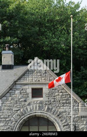 Un edificio accanto alle chiuse del canale Rideau nel centro di Ottawa, con la bandiera canadese che batte mezzo albero. Foto Stock