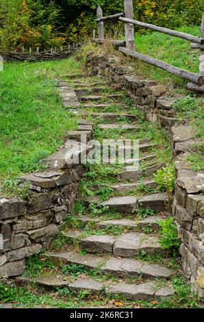 una vecchia scalinata in pietra fatiscente che porta in cima a un prato Foto Stock