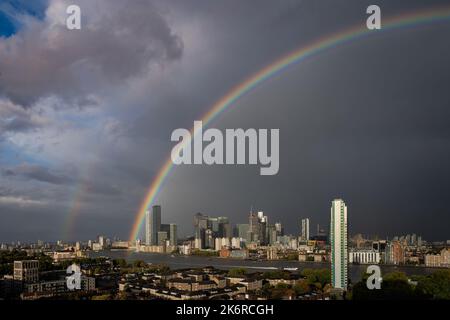 Londra, Regno Unito. 15th ottobre 2022. UK Weather: Un enorme arcobaleno si rompe sugli edifici del parco commerciale di Canary Wharf a est di Londra, mentre un breve temporale pomeridiano si libera. Credit: Guy Corbishley/Alamy Live News Foto Stock