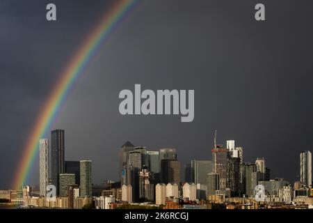 Londra, Regno Unito. 15th ottobre 2022. UK Weather: Un enorme arcobaleno si rompe sugli edifici del parco commerciale di Canary Wharf a est di Londra, mentre un breve temporale pomeridiano si libera. Credit: Guy Corbishley/Alamy Live News Foto Stock