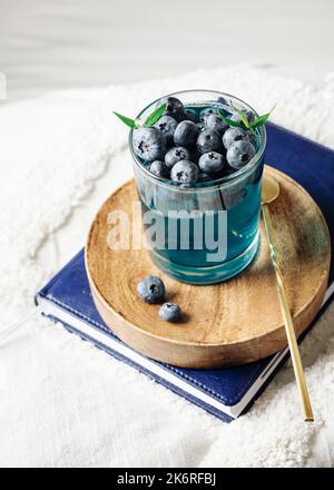 Dessert di gelatina di mirtillo in un bicchiere su un vassoio di legno Foto Stock