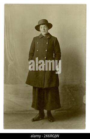 Cartolina ritratto dell'era della prima Guerra Mondiale di una donna degli anni '1900 in uniforme di gonna blu in gesso, cappotto e cappello di paglia blu. Ufficio postale generale (GPO) donne operaie postali / postdonne - che aiutano a consegnare lettere per aiutare lo sforzo bellico sul fronte interno. Donne che lavorano sul fronte domestico. anni '1900 Circa 1916 studi di Herman, Wood Green, Londra, Regno Unito Foto Stock