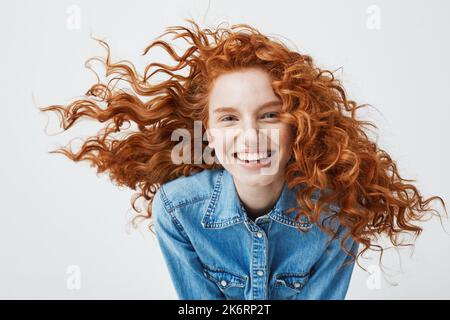 Ritratto di bella ragazza allegra e allegra rossa con capelli volanti sorridente ridendo guardando la macchina fotografica su sfondo bianco. Foto Stock