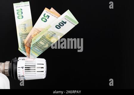Termostato di riscaldamento, dotato di banconote in euro, fondo nero Foto Stock
