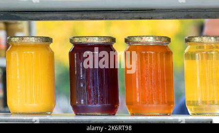 Miele biologico in vasetti di vetro in fila su uno scaffale Foto Stock