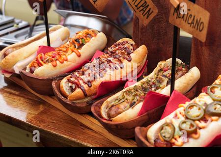 Molti hot dog con vari condimenti e salse. Salsiccia calda per cani alla griglia in un panino fresco. Hot dog piccante con jalapeno, hot dog con senape. Cibo di strada Foto Stock