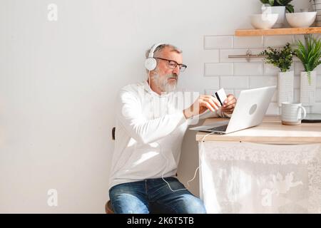 Anziano che effettua pagamenti online utilizzando un computer portatile. Vecchio nonno fare shopping ecommerce con carta di credito. Titolare della carta di debito per Foto Stock