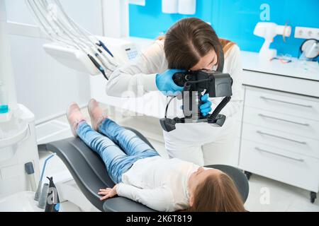 Il dentista scatta foto dei piccoli denti del paziente durante la consultazione Foto Stock