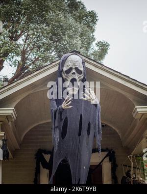 Una grande figura di morte in un mantello nero è appesa davanti all'ingresso di una casa. Foto Stock