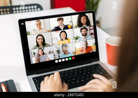 Giovane donna d'affari che videochiama con un computer portatile e colleghi diversi Foto Stock