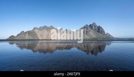 Spiaggia di lava nera, spiaggia sabbiosa e mare, montagne Klatindur riflesso in acqua, Eystrahorn e Kambhorn, promontorio Stokksnes, catena montuosa Foto Stock