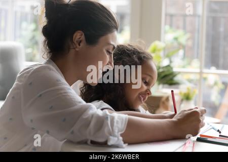 Mamma indiana piccola figlia disegno in sketchbook con matite colorate Foto Stock
