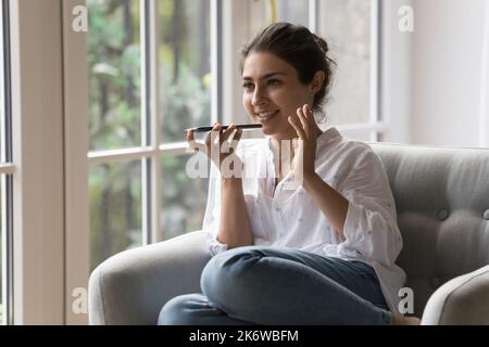 Donna indiana sorridente tiene lo smartphone in conversazione con il vivavoce Foto Stock
