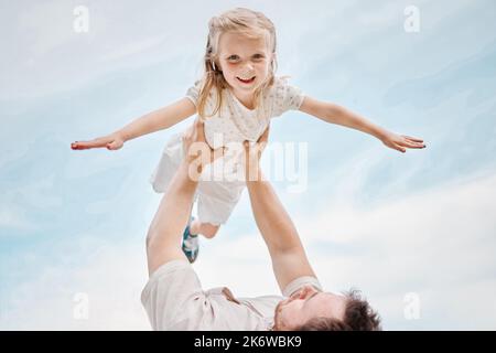 Ritratto ad angolo basso di una adorabile bambina caucasica che viene portata dal suo divertente padre giocoso mentre fuori in un giardino. Sorridente figlia carina Foto Stock