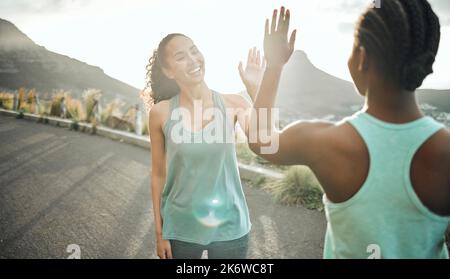 Amici che si allenano insieme, vincete insieme. due giovani donne che si donano un alto cinque mentre si allenano in natura. Foto Stock