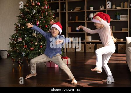 I bambini divertenti ed eccitati ballano alla musica all'albero di Natale Foto Stock