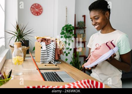 Piccola impresa africana donna proprietario mostrando nuove scarpe di arrivo in live streaming Foto Stock