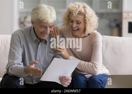 I coniugi ottengono le notizie grandi, leggono la notifica ricevuta della banca ritengono overjoyed Foto Stock