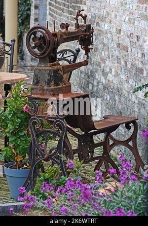 Arrugginita vecchia macchina da cucire posto di fronte alla casa come una decorazione. Alcuni vasi di fiori e deco arrugginito definiscono una sorta di giardino anteriore. Situato a Harl Foto Stock