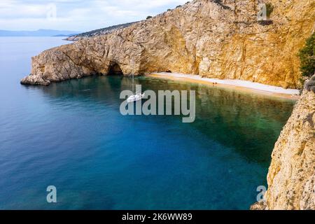 Barca a vela ancorata in una bella baia di spiaggia dorata vicino a Punat, Isola di Krk, Croazia Foto Stock