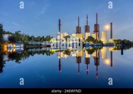 Una centrale combinata di calore ed energia elettrica a Berlino di notte con un perfetto riflesso in acqua Foto Stock