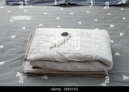 coperta elettrica ripiegata con controller sul letto a composizione orizzontale Foto Stock