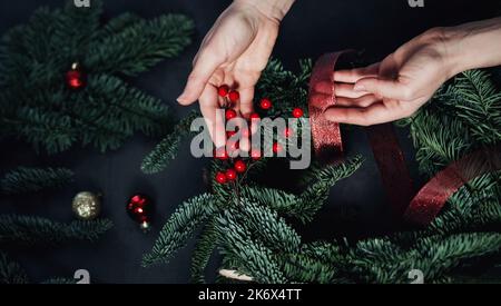 Mani fiorista fare corona di Natale. decorazioni festive Foto Stock