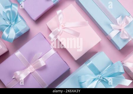 sfondo con scatole regalo colorate con nastri e archi in colori pastello su uno sfondo rosa, il concetto di feste di compleanno, le vendite. Foto Stock