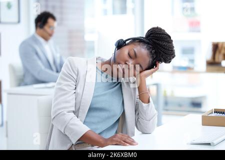 Spianando fuori durante il suo turno. un giovane agente del call center che dorme alla sua scrivania in un ufficio. Foto Stock