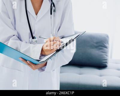 Dottore con lima di carta. La mano delle dottori femminili sta scrivendo su documento medico o note di esame del paziente dalla penna sulla clipboard. Medico in tuta bianca w Foto Stock