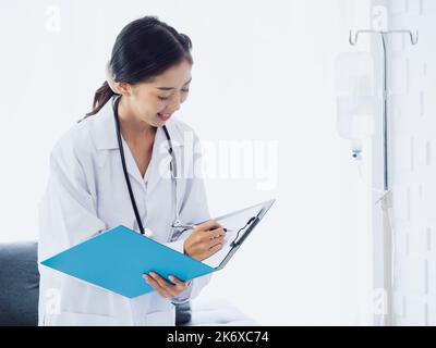 Dottore con lima di carta. Le donne asiatiche dottori scrivere un documento medico o le note di esame del paziente con la penna sulla clipboard. Medico in tuta bianca con wit Foto Stock