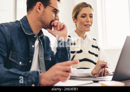 Due uomini d'affari che hanno una discussione con i loro clienti durante una riunione in linea. Uomini d'affari moderni che hanno una videoconferenza in un'offi creativa Foto Stock