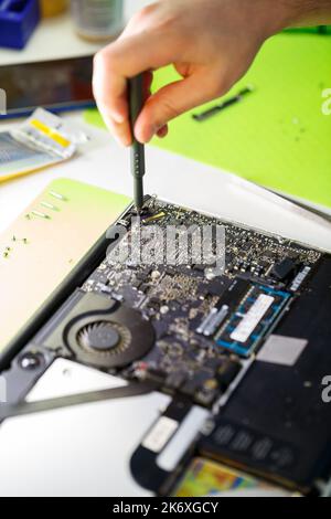 l'uomo pulisce un computer portatile con un attrezzo speciale dalla polvere. Riparazione e manutenzione di computer portatili e PC servizi pubblicitari per la riparazione di componenti elettronici e di elettronica Foto Stock