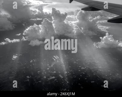 Vista aerea che vola sopra le nuvole e i raggi del sole drammatici e che piercing attraverso le nuvole, paesaggio di sole, luce solare, parte di aereo, ala, Foto Stock