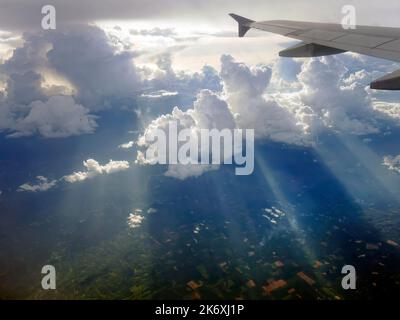 Vista aerea che vola sopra le nuvole e i raggi del sole drammatici e che piercing attraverso le nuvole, il paesaggio soleggiato, la luce del sole, viaggiando in aria, parte o Foto Stock