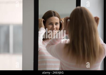 Donna che predica, fare la routine del mattino, in piedi di fronte allo specchio Foto Stock