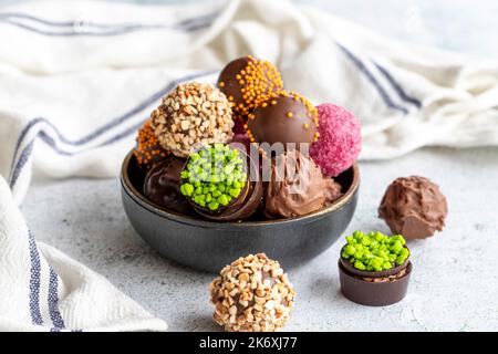 Pralina al cioccolato. Varietà di cioccolatini in ciotola su sfondo grigio. primo piano Foto Stock