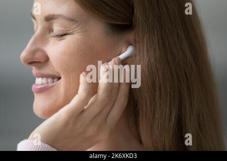 Una donna bella e tranquilla gode di un audio di qualità grazie alle cuffie wireless Foto Stock