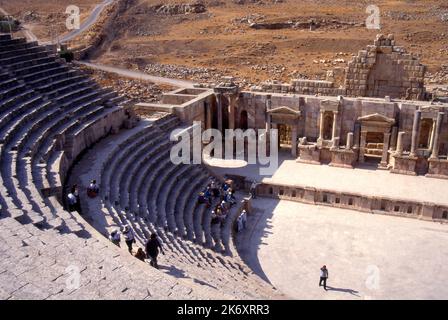 Parte del vecchio teatro romano sud, Jerash, Giordania con i turisti seduti sui sedili Foto Stock