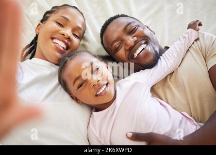 La cosa importante al mondo è la famiglia e l'amore. una madre che si posa a letto prendendo un selfie con la sua famiglia a casa. Foto Stock