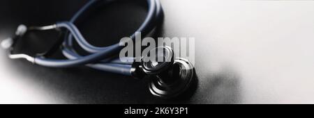 Stetoscopio nero su sfondo scuro opaco Foto Stock