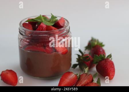 Crema di fragole al cioccolato. Crema al cioccolato servita con fragole fresche tritate. Un dessert facile e veloce, servito in una bottiglia di vetro. Shot su wh Foto Stock