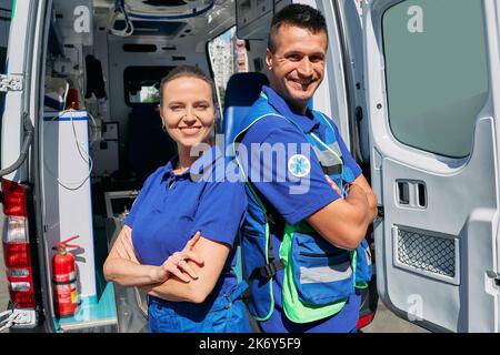 Personale medico di ambulanza. Ritratto del team paramedico in piedi vicino al veicolo dell'ambulanza con braccia incrociate e guardando la telecamera Foto Stock