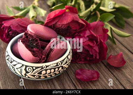Amaretti ripieni di ribes, peonie viola su sfondo di legno Foto Stock