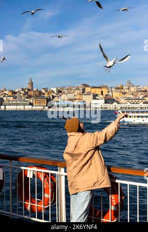 istanbul , Turchia Nowember 12 2021 : giovani turisti che danno cibo ai gabbiani sul traghetto, attività turistica Foto Stock