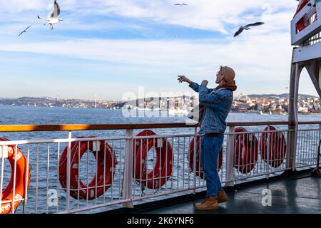 istanbul , Turchia Nowember 12 2021 : giovani turisti che danno cibo ai gabbiani sul traghetto, attività turistica Foto Stock