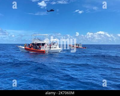 Gli equipaggi delle forze dell'ordine della Guardia costiera salvano le persone da un cabinato da 40 piedi non sicuro e sovraccaricato a circa 20 miglia da Boca Raton, Florida, 12 ottobre 2022. La popolazione è stata trasferita alle autorità delle Bahamas, il 16 ottobre 2022. (STATI UNITI Foto della Guardia Costiera dell'equipaggio di Station Lake Worth) Foto Stock