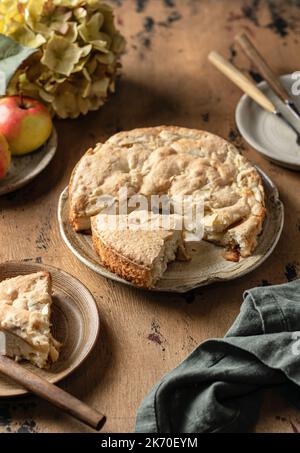 Tradizionale torta di mele charlotte su sfondo di legno. Tempo del tè con il dessert della mela, vita morta del moody autunnale. Orientamento verticale Foto Stock