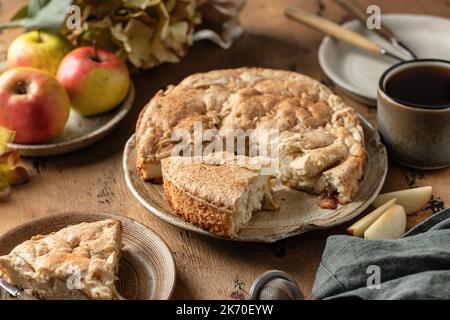 Tradizionale torta di mele charlotte cosparsa di cannella su sfondo di legno. Tempo del tè con il dessert della mela, vita morta del moody autunnale. Orienta orisontale Foto Stock