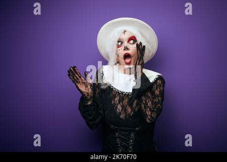 Donna spaventata che sussurra con capelli grigi in costume di Halloween Foto Stock